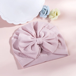 Detail shot of baby pink ribbed knit turban hat with a large decorative bow ornament