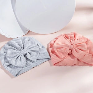 Detailed close-up of pink and grey ribbed cotton baby turbans with large soft bows