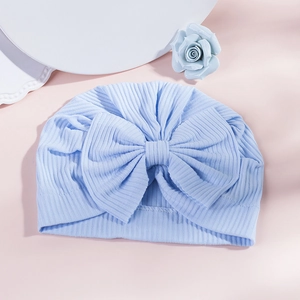 Detail of light blue ribbed knit baby turban hat featuring a large decorative bow tie