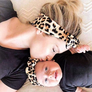 Detail view of mother and baby leopard print headband set on white knit background