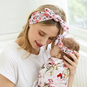 Matching floral headband and baby swaddle blanket set shown in a cozy home setting