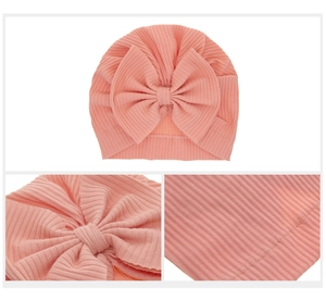 Detailed views of a pink ribbed knit baby hat featuring a large soft bow and fine stitching