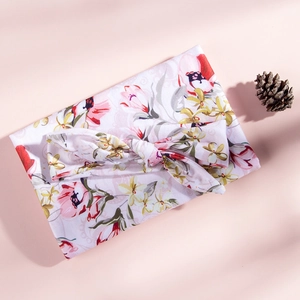 Détail d'une couverture emmaillotage pour bébé à fleurs et bandeau assorti