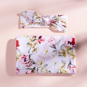 Vue détaillée d'une couverture d'emmaillotage fleurie pour bébé avec bandeau noué assorti