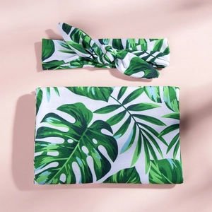 Detail of baby swaddle blanket and rabbit ear headband set with tropical green leaf print