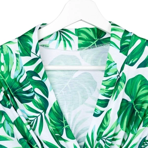 Detail of tropical leaf print maternity robe with monstera and palm patterns on white fabric