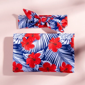 Détail de l'ensemble emmaillotage et bandeau bébé avec motif floral d'hibiscus rouge