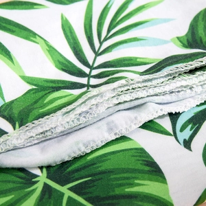 Detail of tropical palm leaf print fabric with high-quality white overlock stitching seams