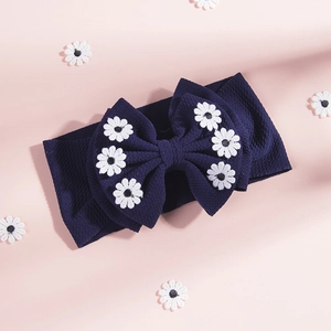 Détail du bandeau bébé bleu marine à texture gaufrée avec grand nœud à fleurs marguerites