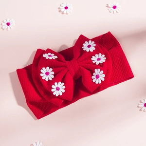 Gros plan du bandeau bébé rouge avec nœud gaufré et broderie de marguerites roses et blanches