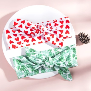Close-up of mother and child rabbit ear headbands with red heart and green leaf prints