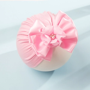Dettaglio del turbante rosa per neonati con fiocco di raso, fiore in tulle e perline
