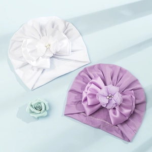 Dettaglio di turbanti per neonati con fiocchi in raso, perle e fiori decorativi