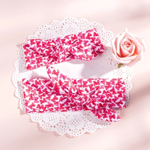 Close-up of mother and child headband set with red polka dot bow pattern on soft knit fabric