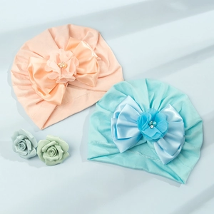 Dettaglio di turbanti per neonati con grandi fiocchi di raso, fiori e perle applicate