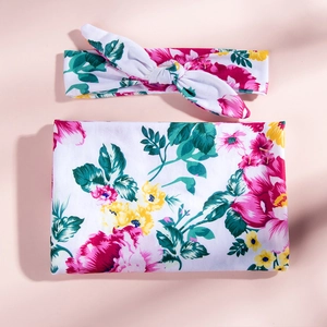 Close-up of floral baby swaddle blanket and matching rabbit ear headband in soft knit fabric
