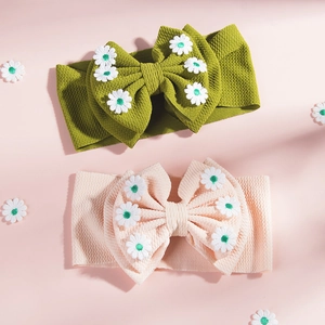 Détail de deux bandeaux bébé avec nœud, broderie marguerite et texture en maille gaufre