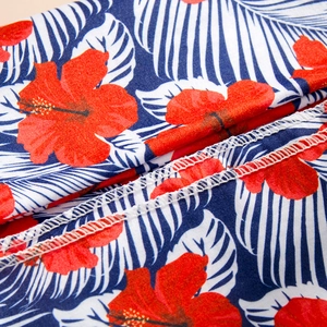 Gros plan d'un tissu à fleurs tropicales avec hibiscus rouges et couture surjet
