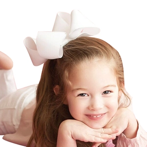 Detail view of a large white grosgrain ribbon bow clip worn by a young girl