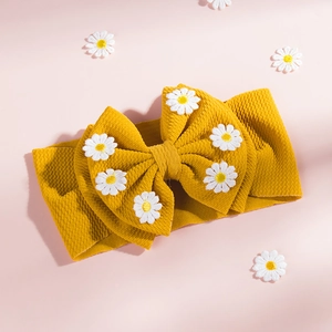 Détail du bandeau jaune pour bébé en tissu texturé orné de petites marguerites blanches