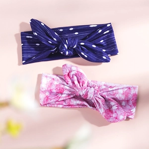 Detail view of two rabbit ear headbands in navy dotted and pink floral patterns