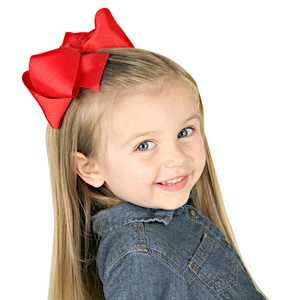 Large red grosgrain ribbon bow hair clip worn by a young girl on a white background