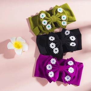 Détail de bandeaux pour bébé en tissu gaufré avec broderie marguerite en vert, noir et violet