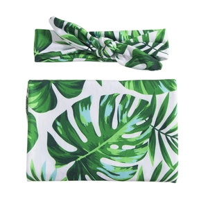 Matching set of green monstera leaf print baby swaddle blanket and knotted headband