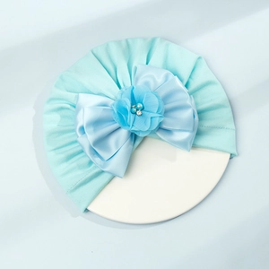 Dettaglio del turbante neonato con fiocco di raso, fiore in chiffon e perle