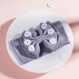 Détail d'un bandeau bébé lavande avec texture gaufrée et nœud à fleurs de marguerite