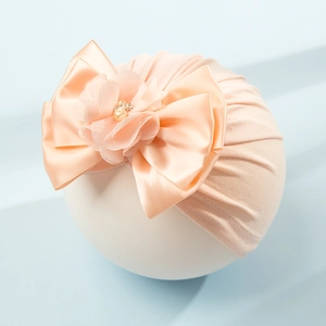 Dettaglio del turbante per neonato con fiocco in raso e fiore in chiffon con perline