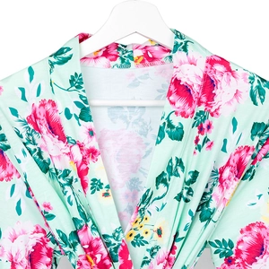 Close-up of mint green floral maternity robe with pink peony print on wooden hanger