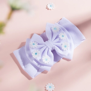 Détail d'un bandeau bébé violet clair en maille gaufrée avec gros nœud et petites marguerites