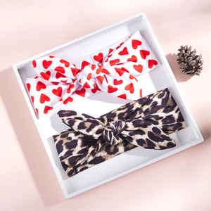Detail of baby headband set featuring red heart and leopard print patterns in wooden tray