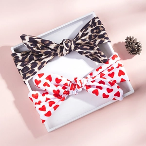 Flat lay of leopard print and red heart pattern bunny ear headbands on a pink background