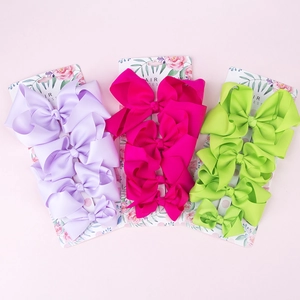 Close-up of three colorful grosgrain ribbon bow clips on floral display cards
