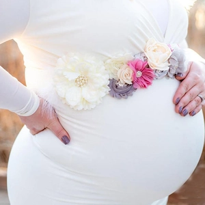 Detail of floral maternity sash with ivory, beige, and pink flowers and pearl accents