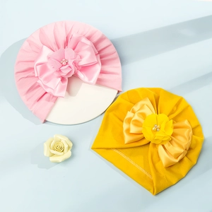 Dettaglio di turbanti per neonati con grandi fiocchi di raso, fiori di tulle e perle