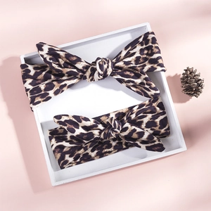 Detail of leopard print knot headbands in a white tray on a soft pink background