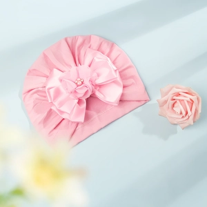 Dettaglio del turbante per neonato con fiocco in raso rosa e decoro con perle