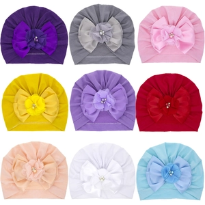 Dettaglio di nove turbanti per neonati in vari colori con fiori e perle decorative