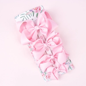 Detailed set of four pink ribbed ribbon bow hair clips on floral retail display card
