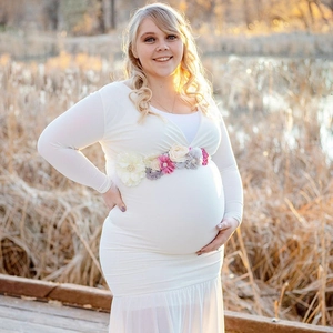 White long sleeve maternity dress with colorful handmade floral sash in soft natural light