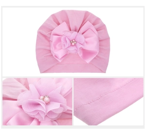 Dettaglio del turbante rosa per neonati con fiore decorativo, perle e maglia morbida
