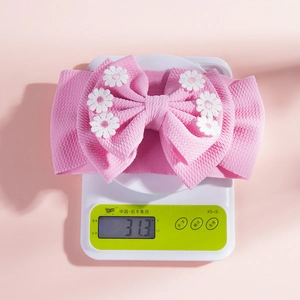 Détail du bandeau rose pour bébé avec broderie de marguerites blanches sur tissu côtelé