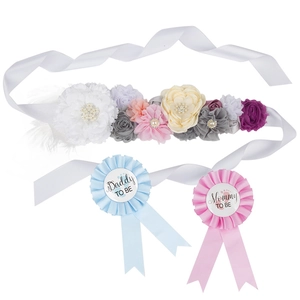 Flat lay of Mom to Be floral sash and Daddy to Be badges for baby shower party