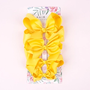 Close-up of four large yellow grosgrain ribbon hair bows on a floral display card