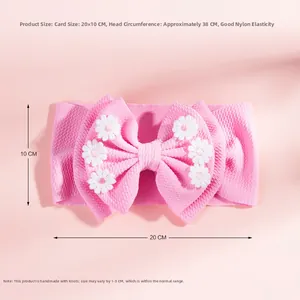 Détail du bandeau bébé rose en maille gaufrée avec six marguerites blanches brodées