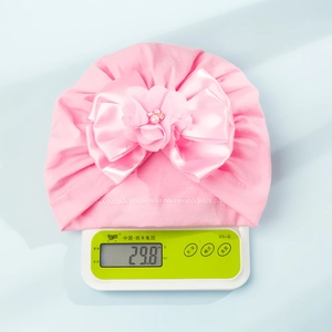 Turbante rosa neonato con grande fiocco di raso e perle, peso 29,8g sulla bilancia