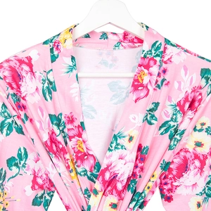 Close-up of pink floral maternity robe with cross V-neck on a white wooden hanger